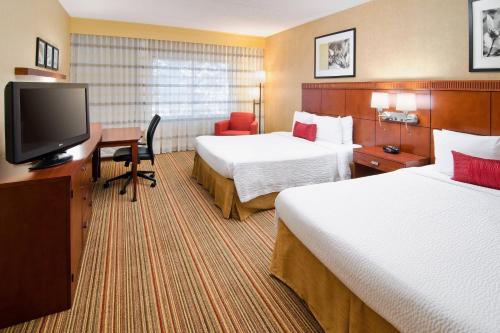 a hotel room with two beds and a flat screen tv at Courtyard by Marriott Albuquerque Airport in Albuquerque