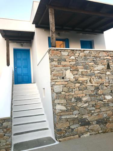 a house with a stone wall and a blue door at Seaside studio with unlimited sea view - Koumbara Beach in Tzamaria