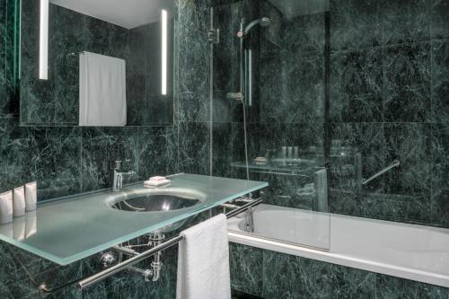 ein Badezimmer mit einem Waschbecken, einer Dusche und einer Badewanne in der Unterkunft AC Hotel Elda by Marriott in Elda