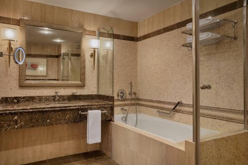 bagno con vasca, lavandino e specchio di Sheraton Club des Pins Resort a Club des Pins