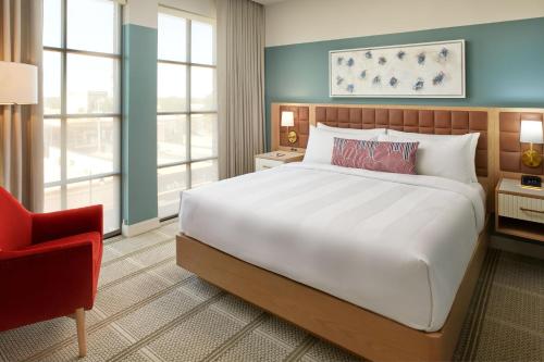 a bedroom with a large bed and a red chair at The Alamite, Tuscaloosa, a Tribute Portfolio Hotel in Tuscaloosa