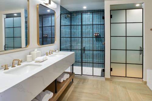 a bathroom with two sinks and a large mirror at The Alamite, Tuscaloosa, a Tribute Portfolio Hotel in Tuscaloosa