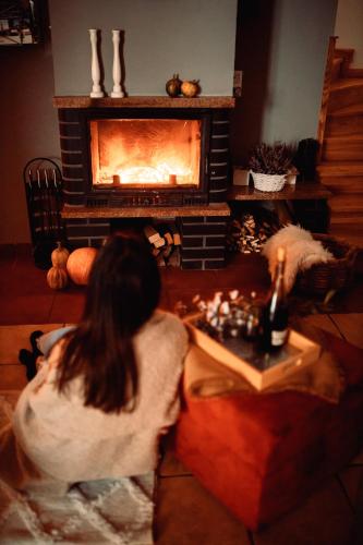 a woman sitting in a living room with a fireplace at Domki RADAWA na Kliszówce in Radawa