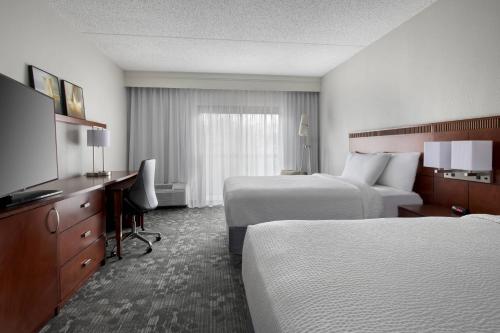 a hotel room with two beds and a flat screen tv at Courtyard by Marriott Lincroft Red Bank in Red Bank