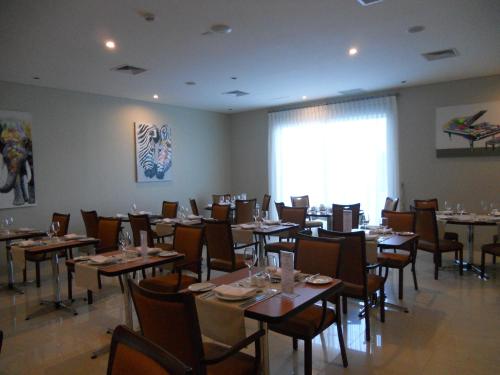 a dining room with tables and chairs and a large window at Hotel Diego de Almagro Chillan in Chillán