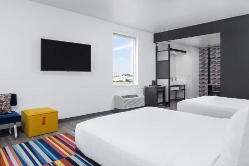 a white room with a bed and a tv at Aloft Oklahoma City Quail Springs in Oklahoma City