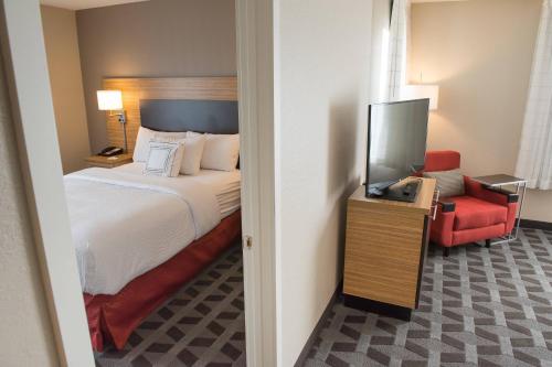 a hotel room with a bed and a red chair at TownePlace Suites by Marriott Battle Creek in Battle Creek
