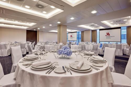 a banquet hall with white tables and white chairs at Basel Marriott Hotel in Basel