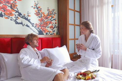 un hombre y una mujer sentados en una cama en CUNDA BARADİEL Hotel en Ayvalık