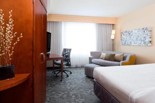 a hotel room with a bed and a couch and a desk at Courtyard Des Moines Ankeny in Ankeny
