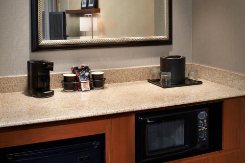 a kitchen counter with a microwave and a mirror at Courtyard Detroit Dearborn in Dearborn