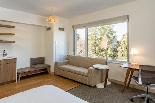 a bedroom with a couch and a desk and a window at Element Bend in Bend