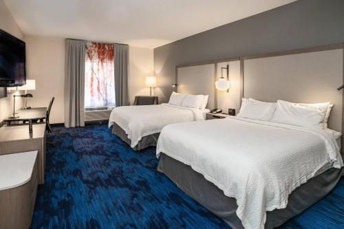 a hotel room with two beds and a flat screen tv at Fairfield Inn & Suites by Marriott Kearney in Kearney