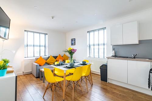 a kitchen and dining room with a table and yellow chairs at Greyfriars in Clacton-on-Sea