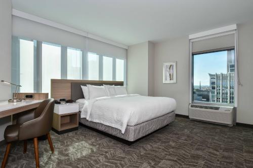 SpringHill Suites by Marriott Charlotte City Center في تشارلوت: غرفة في الفندق بها سرير ومكتب ونافذة