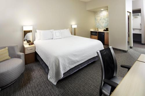 ブライトンにあるCourtyard Detroit Brightonのベッド、デスク、椅子が備わるホテルルームです。