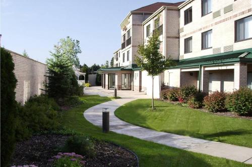 a building with a walkway in front of a yard at Courtyard Detroit Brighton in Brighton