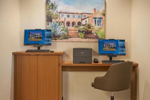 two computer monitors sitting on top of a desk at SpringHill Suites by Marriott Winter Park in Orlando