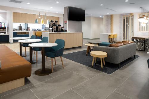 ein Wohnzimmer mit Tischen und einem Sofa sowie eine Küche in der Unterkunft TownePlace Suites by Marriott Sidney in Sidney