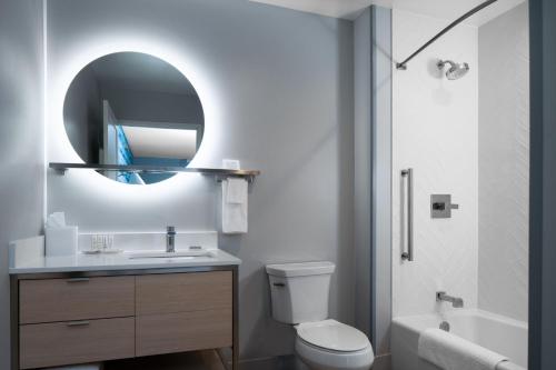 a bathroom with a toilet and a sink and a mirror at TownePlace Suites by Marriott Sidney in Sidney