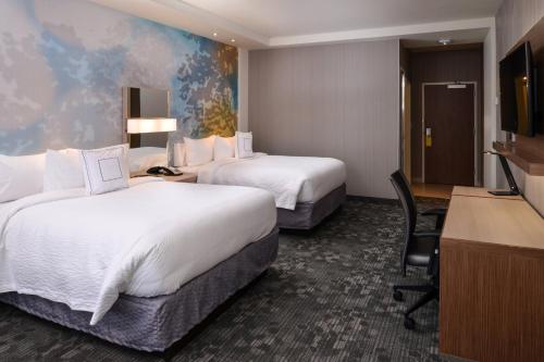 a hotel room with two beds and a desk at Courtyard by Marriott St. Louis St. Peters in Saint Peters