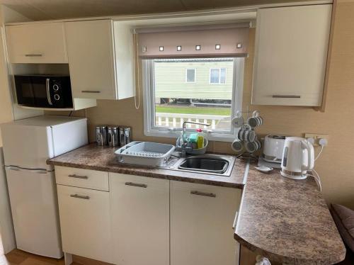 a small kitchen with a sink and a refrigerator at Chalet 40, Cleethorpes in Humberston