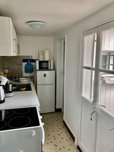 Il comprend une cuisine équipée d'une cuisinière et d'un réfrigérateur blancs. dans l'établissement Charmante maisonnette proche plage et commerces, à Blonville-sur-Mer