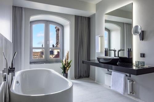 uma casa de banho com uma banheira, um lavatório e um espelho. em Hotel Luc, Autograph Collection em Berlim