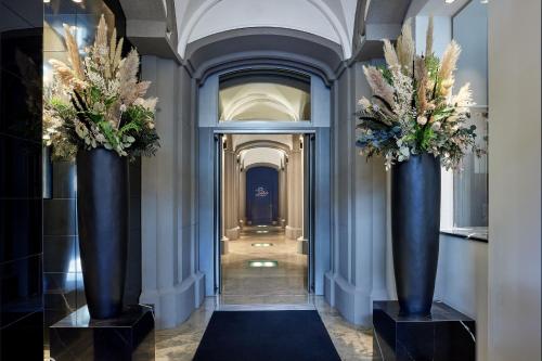 un couloir avec deux grands vases bleus avec des fleurs sur eux dans l'établissement Hotel Luc, Autograph Collection, à Berlin