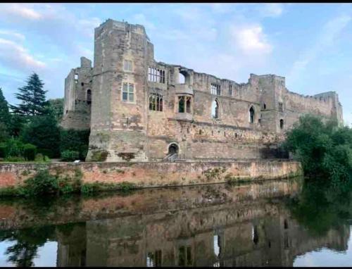 um velho castelo é refletido em um corpo de água em Private Entranced Guest suite/Kitchenette/Patio em Balderton