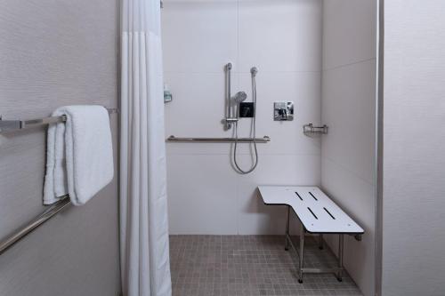 a white bathroom with a shower and a sink at Courtyard by Marriott Dallas Richardson at Spring Valley in Richardson