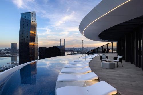 a pool on the roof of a building with chairs and tables at Melbourne Marriott Hotel Docklands in Melbourne