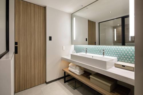 La salle de bains est pourvue d'un lavabo et d'un miroir. dans l'établissement Courtyard by Marriott Osaka Honmachi, à Osaka
