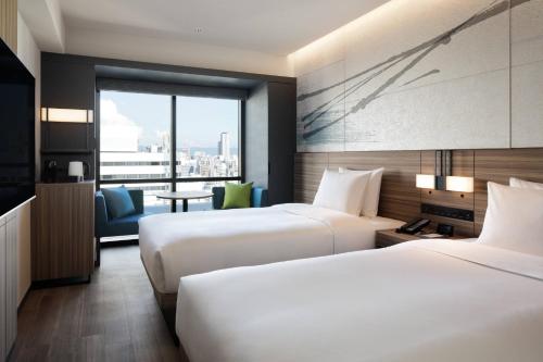 two beds in a hotel room with a view at Courtyard by Marriott Osaka Honmachi in Osaka