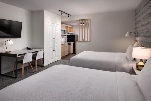 a hotel room with two beds and a desk at TownePlace Suites by Marriott West Kelowna in West Kelowna