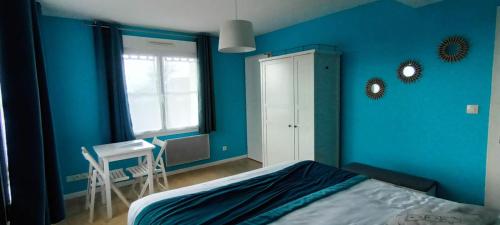 a blue bedroom with a bed and a window and a desk at Escales dans les dunes in Créances