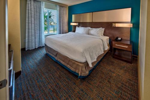 Residence Inn Fort Lauderdale Pompano Beach Central في بومبانو بيتش: غرفة فندقية بسرير كبير ونافذة