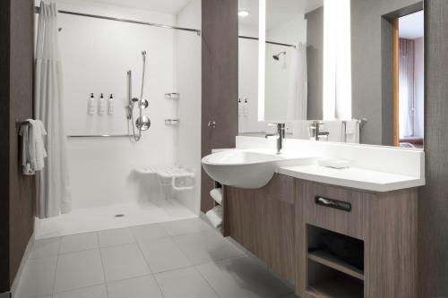 uma casa de banho branca com um lavatório e um chuveiro em SpringHill Suites by Marriott Charlotte Airport Lake Pointe em Charlotte