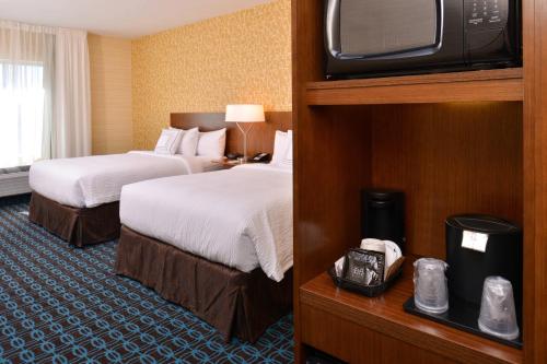 a hotel room with two beds and a flat screen tv at Fairfield Inn & Suites Farmington in Farmington