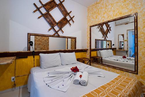a bedroom with a bed with two towels and mirrors at Hotel Pousada Natural in Brotas