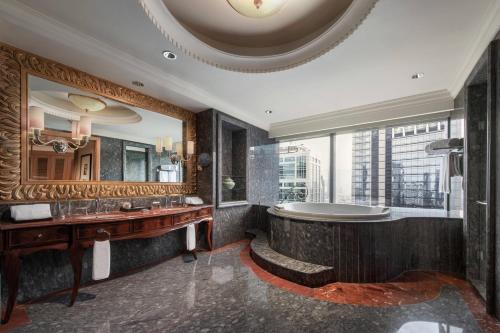 a bathroom with a tub and a large mirror at The Ritz-Carlton Jakarta, Mega Kuningan in Jakarta