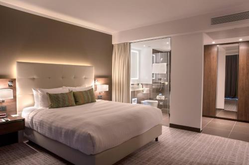 a bedroom with a large bed and a bathroom at Courtyard by Marriott Wolfsburg in Wolfsburg
