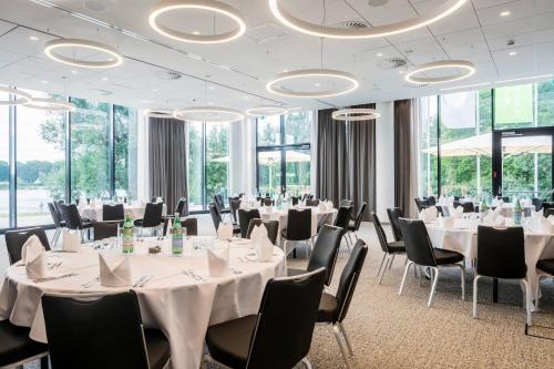 uma sala de conferências com mesas e cadeiras brancas e janelas em Courtyard by Marriott Wolfsburg em Wolfsburg