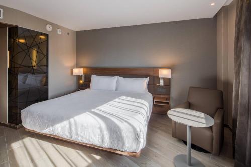 a bedroom with a large bed and a chair at AC Hotel by Marriott Guadalajara Expo in Guadalajara
