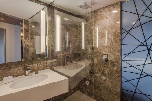 a bathroom with a sink and a glass shower at AC Hotel by Marriott Guadalajara Expo in Guadalajara