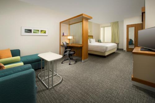 une chambre d'hôtel avec un canapé, un lit et une télévision dans l'établissement SpringHill Suites Bridgeport Clarksburg, à Bridgeport
