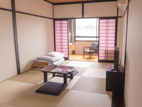 una habitación con una mesa y una habitación con puertas rosas en Wakatake, en Katsuura
