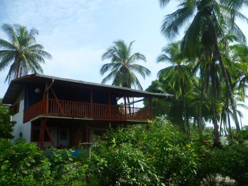 a house with a balcony and palm trees at Cabaña El Bien Germina Ya in El Valle