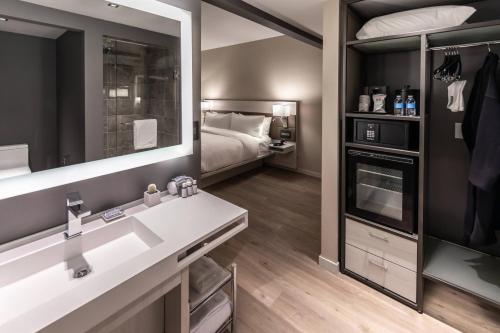 a bathroom with a bed and a sink and a mirror at AC Hotel by Marriott Fort Worth Downtown in Fort Worth