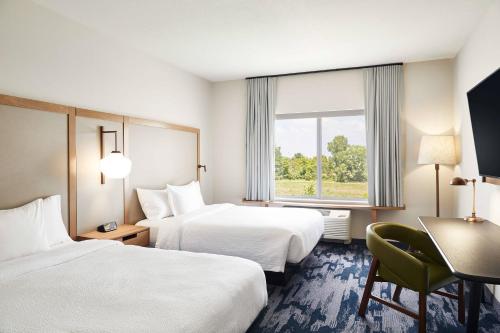 a hotel room with two beds and a desk and a window at Fairfield Inn & Suites by Marriott Kansas City Belton in Belton